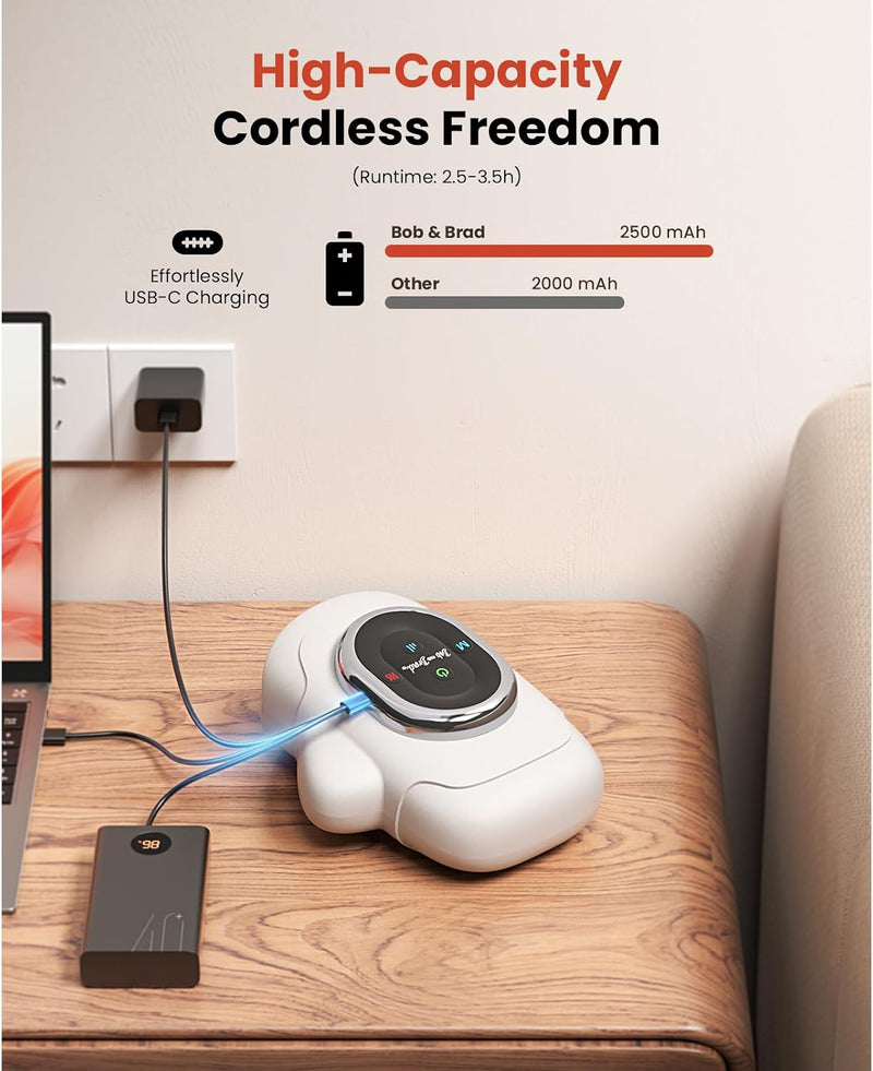 A white hand massager sits on a wooden table, connected to a laptop via a cable and a black rectangular accessory. The scene includes marketing text at the top comparing battery capacities, and part of a chair is visible on the right. Text includes: High-Capacity Cordless Freedom (Runtime: 2.5-3.5h) Effortless USB-C charging.