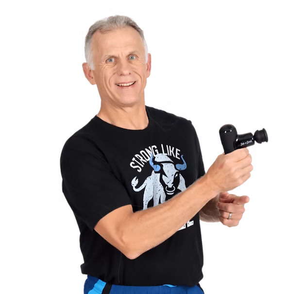 Brad is wearing a black graphic T-shirt with a bull design and the words 'STRONG LIKE' and holds a black Q2 massage gun against a solid white background.