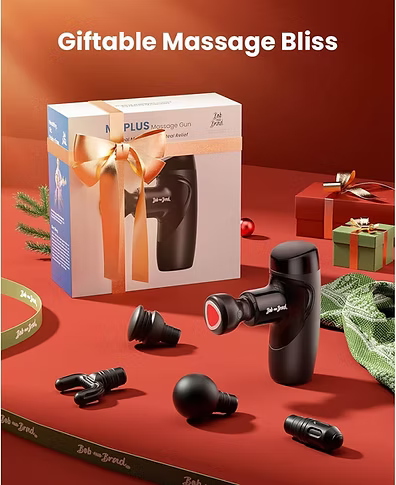 A boxed massage gun set displayed on a red surface with the product and several interchangeable heads arranged around it. The box reads 'M7 PLUS Massage Gun' and 'New Edition,' and the headline at the top says 'Giftable Massage Bliss.