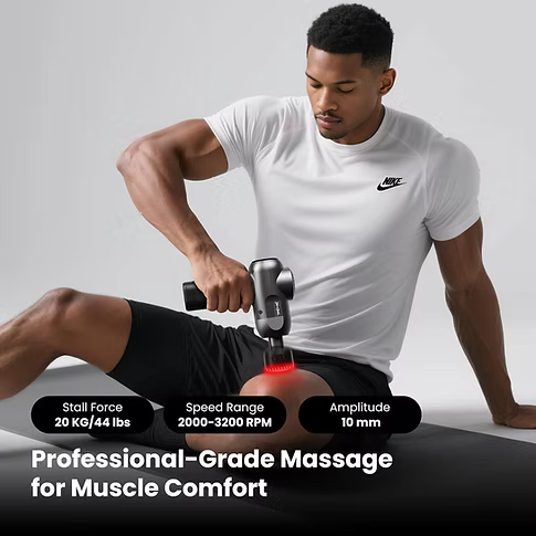 A man in a white Nike T-shirt and black shorts uses a handheld massage gun on his quad while sitting on a black mat. The image features text overlays detailing product specifications: 'Stall Force 20 Ko/44 lbs', 'Speed Range 2000-3200 RPM', 'Amplitude 10 mm', and 'Professional-Grade Massage for Muscle Comfort