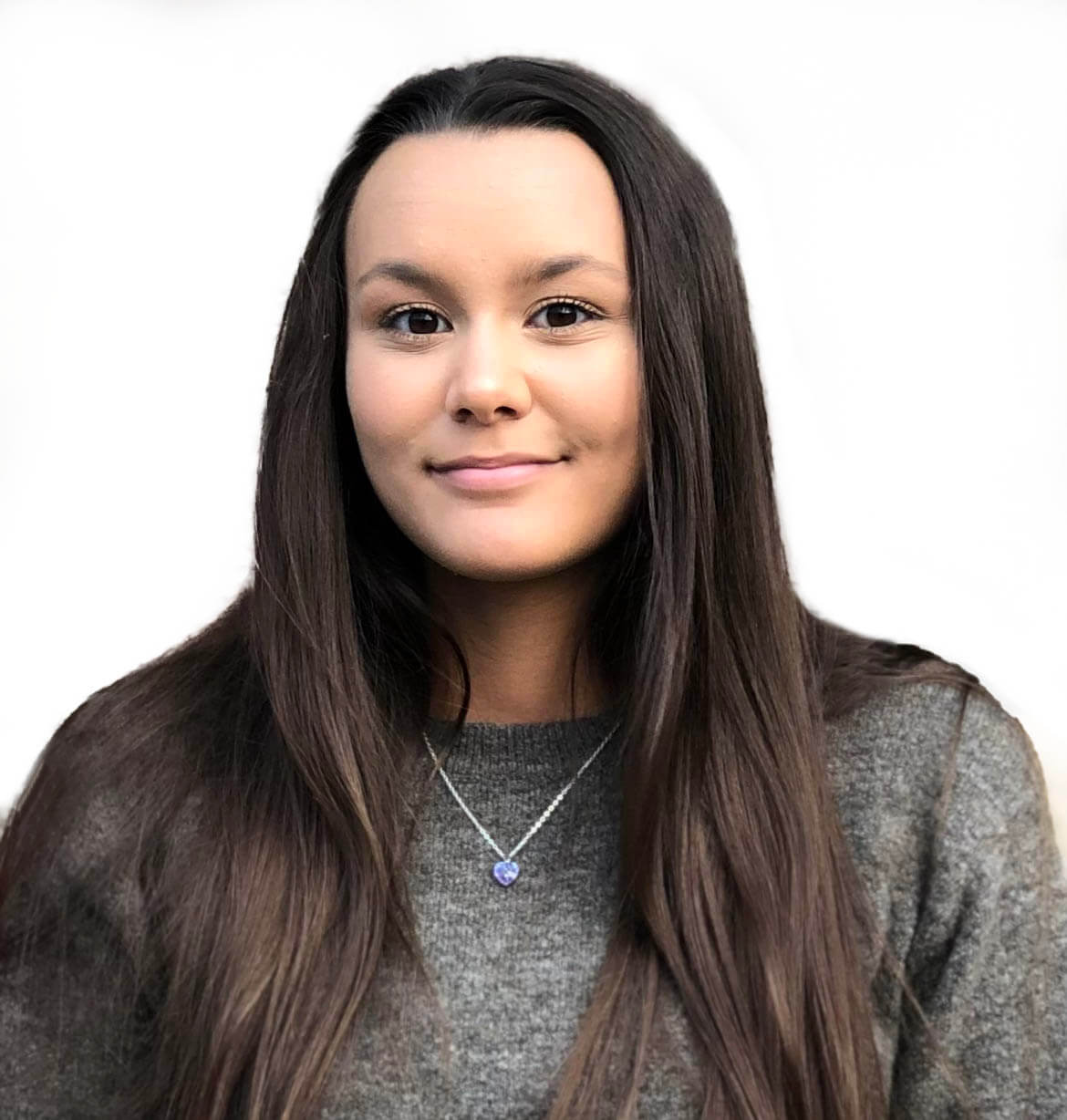 Rain with long dark brown hair wearing a gray knit sweater and a silver necklace with a small purple heart pendant, photographed against a plain white background.