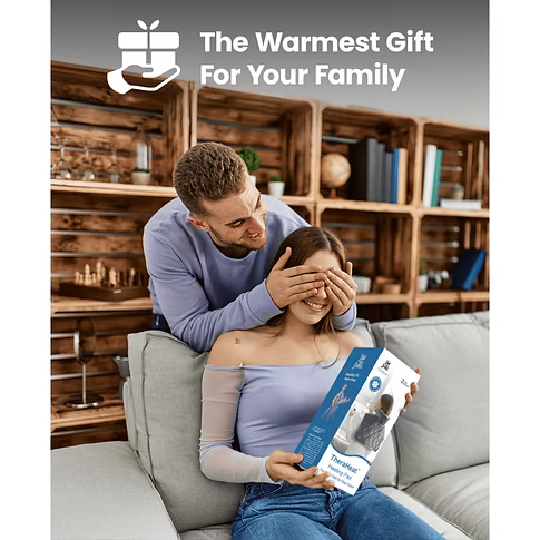 Man covering a woman's eyes with a heating pad product box on her lap in a cozy living room setting.